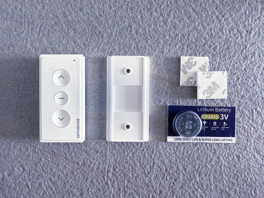Zemismart MTP1 remote with back cover removed, wall adhesives and supplied battery