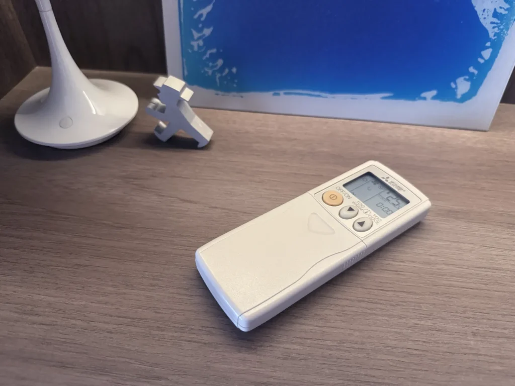 Mitsubishi Electric Starmex air conditioner remote controller on a wooden shelf